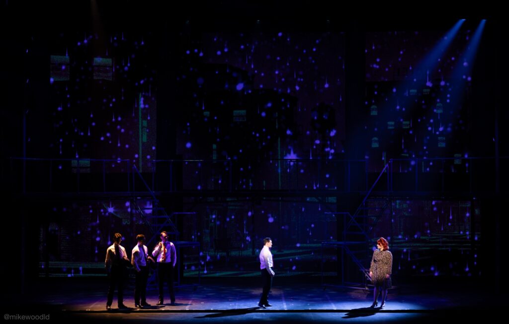 Jersey Boys — Frankie standing apart from his band, separated by a diagonal back-light source