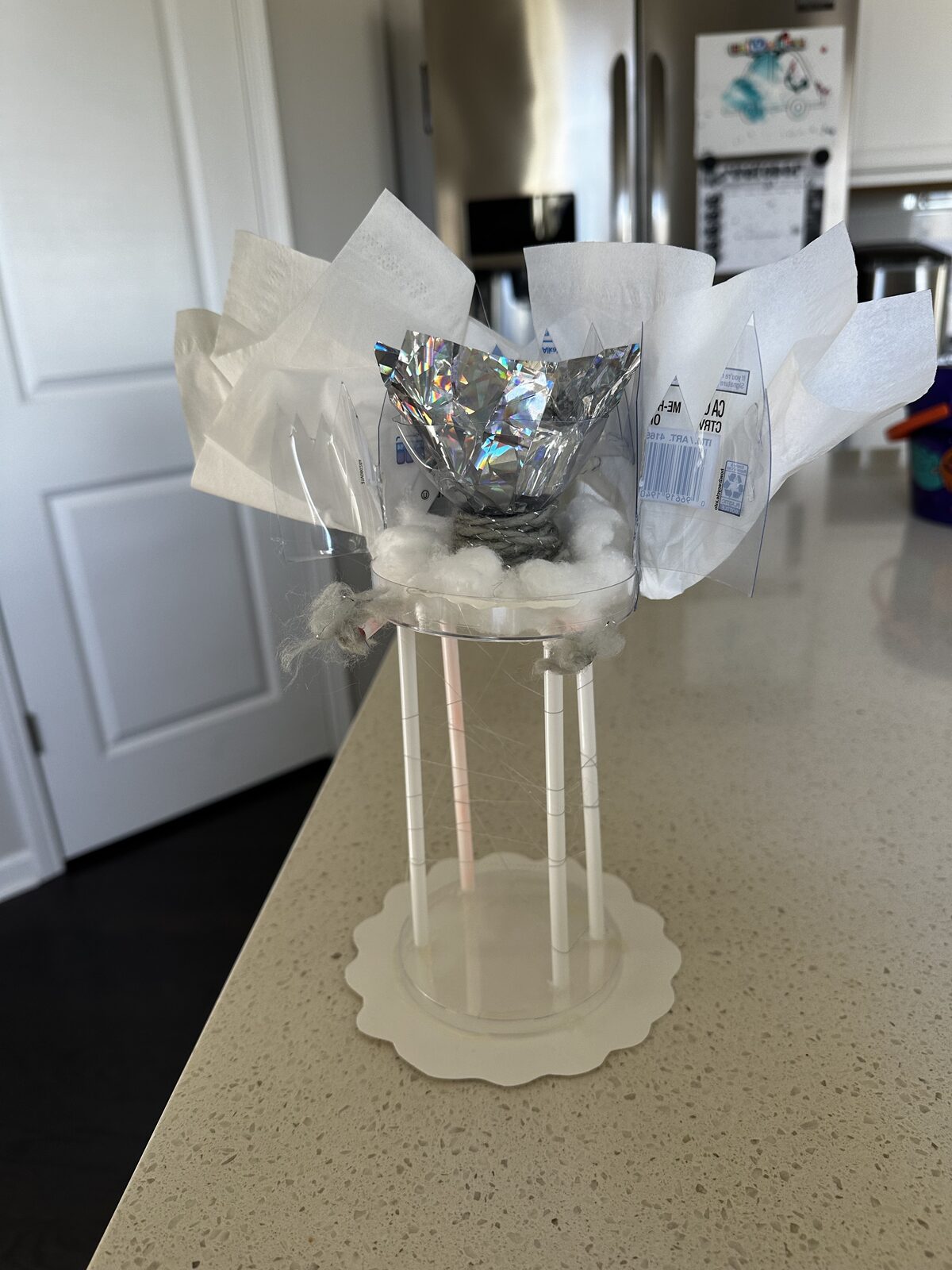 Livia Stetson · Form & Texture project: a paper-plate base, four straw pillars, cotton-ball clouds, a metallic silver crinkled centerpiece, and tissue-paper drapery flowing outward